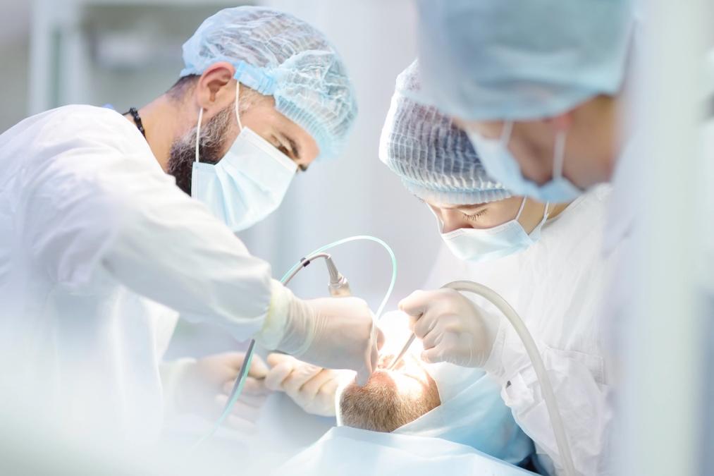 a group of dentists are working on a patient in an operating room .