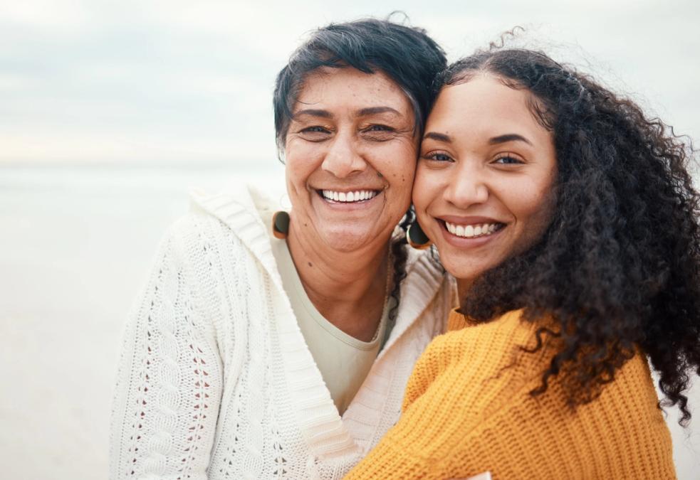 Two smiling women, one older and one younger, outdoors.