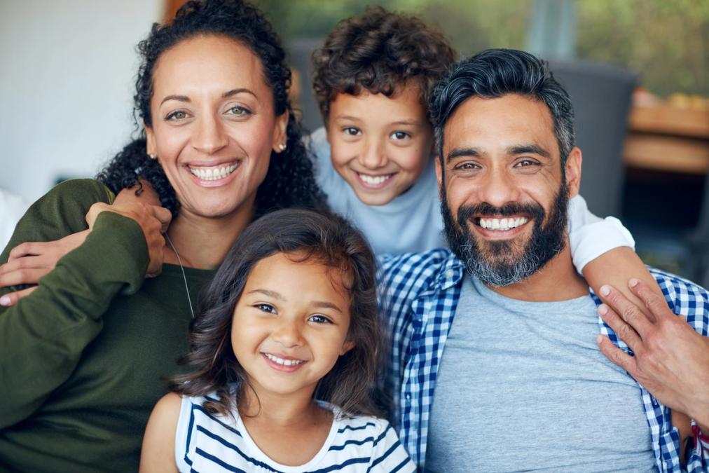 A smiling family of four: a mother, father, daughter, and son.