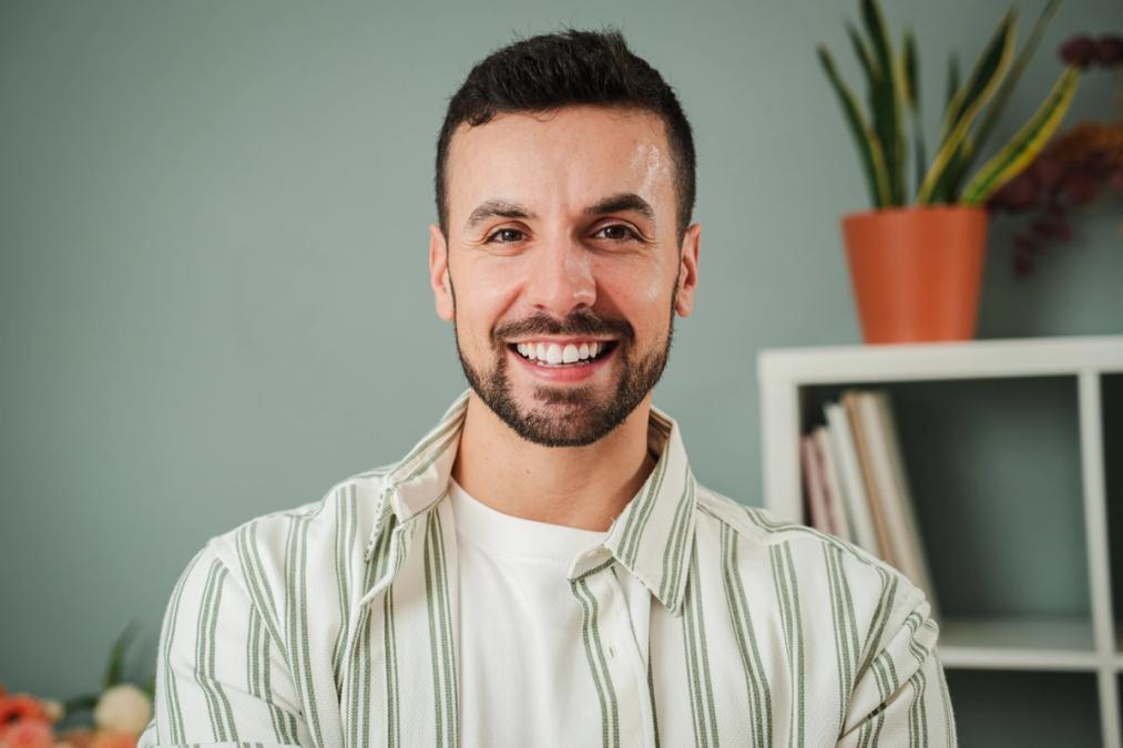 A smiling man with a beard in a striped shirt.
